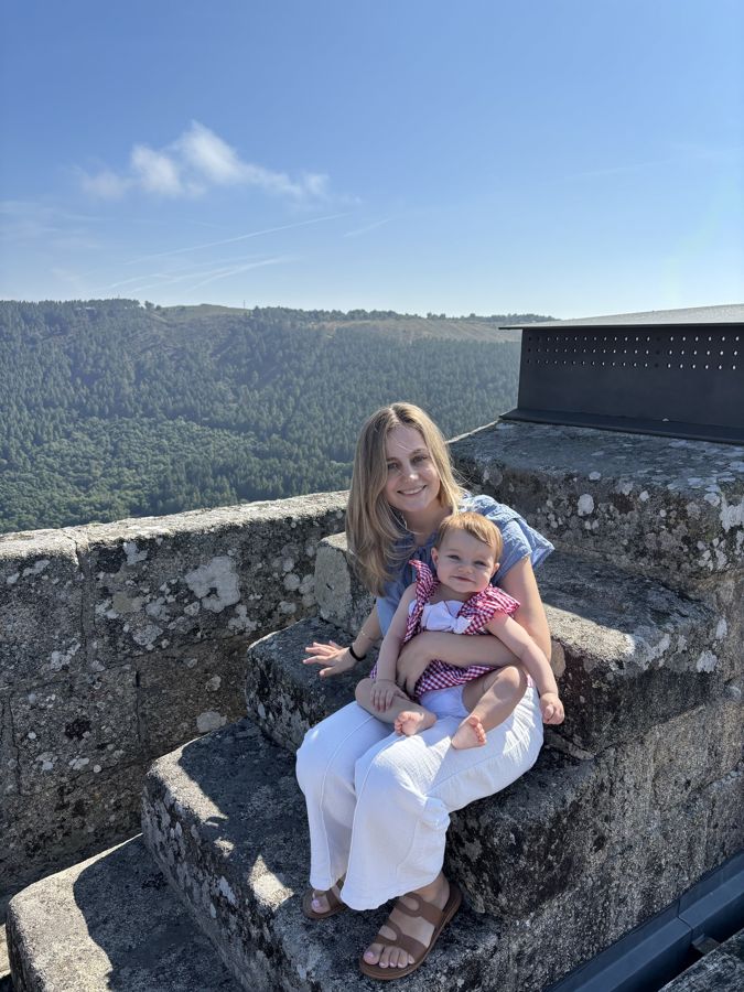 Anabela sonriendo con Olivia en brazos, con un valle de fondo